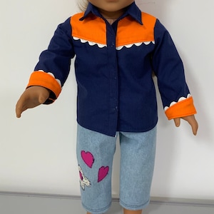 May include: A blue and orange long-sleeved shirt with white trim and a button-up front. The shirt is paired with light blue denim pants with pink heart patches.