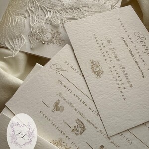 Puede incluir: Elegante juego de invitaciones de boda con tarjetas color crema con texto dorado y elementos florales decorativos. La invitaci&oacute;n incluye detalles para la recepci&oacute;n en The Grand Ballroom, The Ritz-Carlton, Fallbrook, California. Tambi&eacute;n se incluyen los detalles de RSVP.