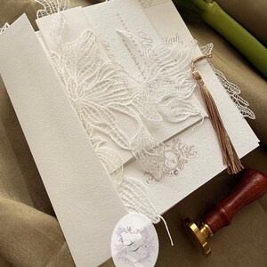 Puede incluir: Juego de invitaciones de boda marfil con delicados detalles de encaje. La invitaci&oacute;n presenta una escritura elegante y una borla. Tambi&eacute;n hay un sello de madera con un sello dorado, junto con una etiqueta con "INK ART".