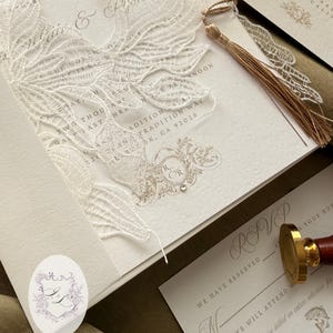 Puede incluir: Elegante juego de invitaciones de boda con un dise&ntilde;o floral cortado con l&aacute;ser. La invitaci&oacute;n incluye los nombres "Ryan" y "Katie", junto con los detalles de RSVP. Una borla dorada y un sello de cera a&ntilde;aden un toque de lujo. El conjunto es en tonos neutros.
