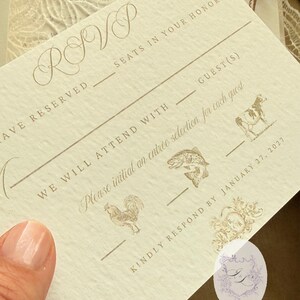 Puede incluir: Tarjeta RSVP color crema con escritura elegante e ilustraciones de un pez, una vaca y un gallo. La tarjeta incluye secciones para completar con los nombres de los invitados y las selecciones de men&uacute;. El texto "INK AND LOVE" es visible.