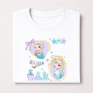 May include: White t-shirt with a cartoon illustration of a princess with blonde braids, wearing a crown and a teal dress. The design includes stars, a bow, and the name "ELSA". The princess is holding a star and a drink.