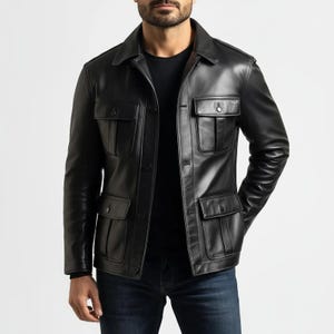 Puede incluir: Chaqueta de cuero negra con cuatro bolsillos delanteros y cuello. La chaqueta tiene cierre de botones y se usa sobre una camisa negra y vaqueros azules. El diseño de la chaqueta es clásico y elegante.