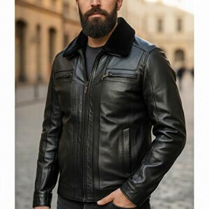 May include: Black leather jacket featuring a black fur collar. The jacket has a zip-up front, multiple pockets, and a tailored fit. The person is wearing black jeans. The background is a blurred street scene.