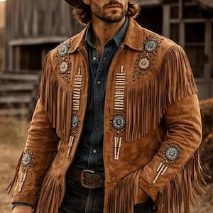 Op de afbeelding: Een bruin suède jasje met lange franjes, turquoisekleurige ronde versieringen en verticale rijen witte kralen op de borst en mouwen, gedragen met een bijpassende bruine cowboyhoed en een donkerblauw overhemd met knoopsluiting.