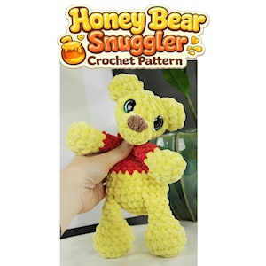 Può includere: Un orsacchiotto di peluche lavorato all'uncinetto in giallo e rosso con grandi occhi scuri e un naso marrone. Il testo Honey Bear Snuggler Crochet Pattern è visualizzato in alto con un carattere stilizzato e un vasetto di miele vicino a Honey.