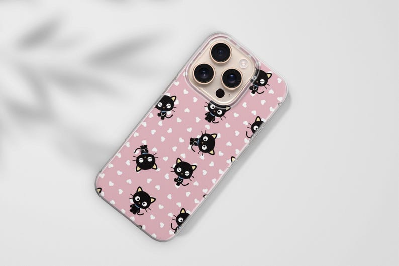 Op de afbeelding: Een telefoonhoesje met een roze achtergrond en een patroon van zwarte kattenillustraties en witte hartjes. De telefoonhoes is gemaakt van een transparant materiaal en heeft een uitsparing voor de cameralens.
