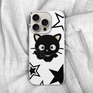Op de afbeelding: Een witte telefoonhoes met een zwart cartoonkatontwerp dat een vredesteken geeft, en zwarte stervormen. De telefoonhoes heeft een cameramodule met drie lenzen.
