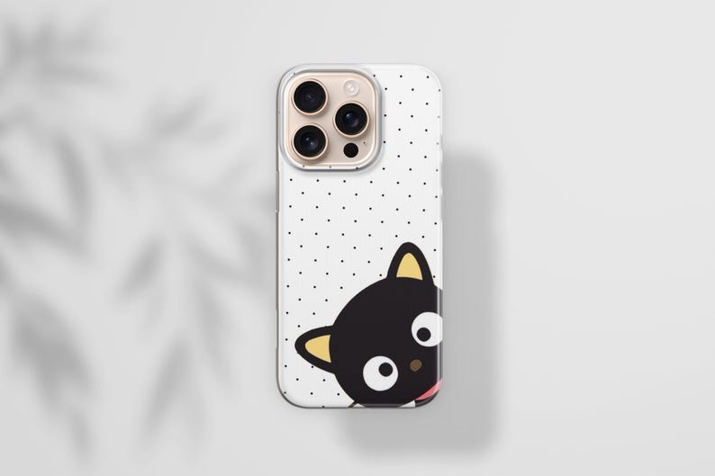 Op de afbeelding: Een witte iPhone-hoes met een zwart kattenstripontwerp. De hoes heeft een stippenpatroon en een transparante rand. De kat heeft gele oren en een roze tong. De telefoonhoes is ontworpen om de telefoon te beschermen tegen krassen en beschadigingen.