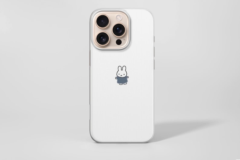 May include: A white phone case with a clear border. The case features a small cartoon bunny wearing a blue outfit. The phone's camera lenses are visible at the top. The background is a solid white.
