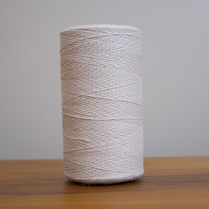 May include: A spool of white cotton thread.