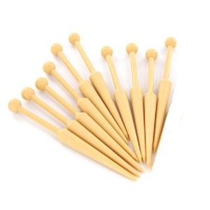 K&ouml;nnte beinhalten: Ein Satz von zehn Stricknadeln aus Holz mit abgerundeten Spitzen und sich verj&uuml;ngenden Spitzen. Die Nadeln sind beigefarben und in F&auml;cherform angeordnet.