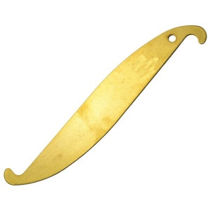 May include: A golden, curved metal tool with a hook at one end and a rounded curve at the other. It features a small hole near the hook. The tool has a slightly textured surface and is designed with a curved shape.