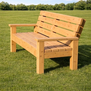 Könnte beinhalten: Eine Gartenbank aus Holz mit Lattenrücken und Sitzfläche sowie Armlehnen. Die Bank ist aus hellem Holz gefertigt und steht auf einer Rasenfläche unter blauem Himmel.