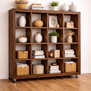 May include: A dark brown wooden bookshelf with multiple square compartments. The shelves are filled with decorative items like vases, baskets, books, and small plants. The bookshelf is on wheels and sits on a wooden floor.