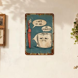 Könnte beinhalten: Ein verwittertes Metallschild mit einer Cartoon-Zahnbürste und einer Toilettenpapierrolle mit Gesichtern. Die Zahnbürste sagt: „Ich hasse meinen Job...“ und das Toilettenpapier antwortet: „Oh bitte!!!“ Das Schild hat einen tealfarbenen Hintergrund und einen rostigen Rand.