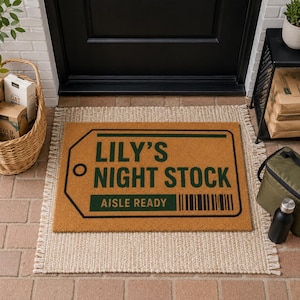 Può includere: Uno zerbino rettangolare in fibra di cocco color cuoio con una grafica verde scuro a forma di etichetta di spedizione. Il testo recita LILY'S NIGHT STOCK e AISLE READY, accompagnato da un codice a barre verticale. Il design ha un bordo nero.