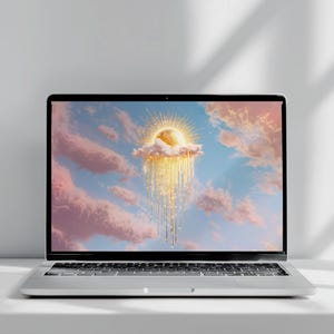 May include: A silver laptop displaying a digital artwork of a glowing golden sun resting on a pink cloud, with shimmering golden light rays cascading downward against a soft blue and pink sky filled with scattered clouds.