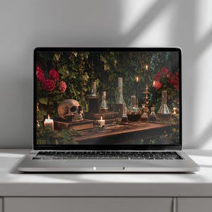 May include: A silver laptop displaying a screen image of a dark wooden table featuring a human skull, various glass apothecary bottles, lit candles, and red roses set against a backdrop of dense green ivy foliage and dark shadows.