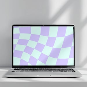 May include: A silver laptop with a screen displaying a distorted, wavy checkerboard pattern in alternating light purple and pale mint green squares. The device features a standard keyboard and a thin black bezel surrounding the digital display.
