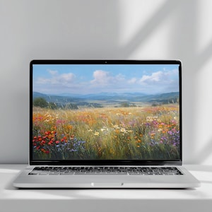 May include: A silver laptop with a black keyboard and screen bezel displaying a vibrant landscape image of a wildflower meadow under a blue sky with white clouds. The device features a thin frame and a standard QWERTY keyboard layout.
