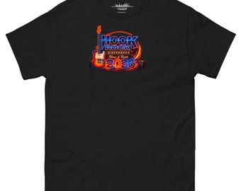 Könnte beinhalten: Schwarzes T-Shirt mit einem Neon-Grafikdesign, das "HOOK ROCK" und "2026" zeigt. Eine Gitarre befindet sich über "Blues & Roots" und "DIEPENBEEK". Das T-Shirt hat einen Rundhalsausschnitt und kurze Ärmel, ein klassisches Design.