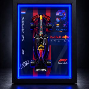 May include: A framed display featuring a miniature black and red Red Bull Racing Formula 1 car, a portrait of Max Verstappen in a racing helmet, the text Max Verstappen, RB21, Red Bull Racing, and Formula 1, with a bright blue neon light border.