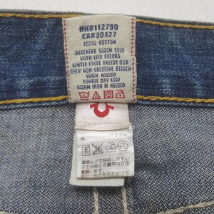 May include: Close-up of a denim jeans tag with care instructions. The tag includes text: "#N112790, CA#30427, 100% COTTON, MACHINE WASH COLD WITH LIKE COLORS, GENTLE CYCLE INSIDE OUT, ONLY NON-CHLORINE BLEACH WHEN NEEDED, TUMBLE DRY LOW, WARM IRON IF NEEDED."