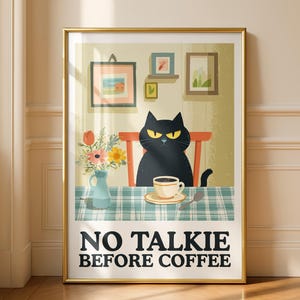 May include: A framed art print featuring a black cat with yellow eyes sitting at a table with a cup of coffee. The table has a blue and white checkered tablecloth. The text "NO TALKIE BEFORE COFFEE" is at the bottom.