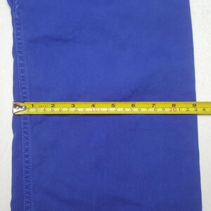 Puede incluir: Primer plano de una tela azul con una cinta m&eacute;trica amarilla y negra. La cinta muestra medidas en cent&iacute;metros, con la tela extendi&eacute;ndose hasta aproximadamente 23 cm.