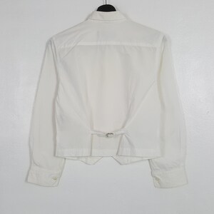 May include: A white ceramic mug with a black handle and the text "But First, Coffee" in a handwritten style. The mug is on a white surface. The mug is approximately 4 inches tall.