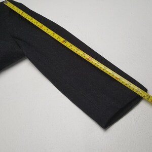 May include: A white ceramic mug with a black handle and the text "But First, Coffee" in a bold, black font. The mug is set against a blurred background, suggesting a cozy setting.