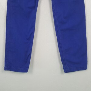 Puede incluir: Un pantal&oacute;n azul vibrante. El pantal&oacute;n est&aacute; hecho de una tela lisa y s&oacute;lida y presenta costuras visibles a lo largo de las costuras. Las perneras son rectas y ligeramente c&oacute;nicas hacia la parte inferior.
