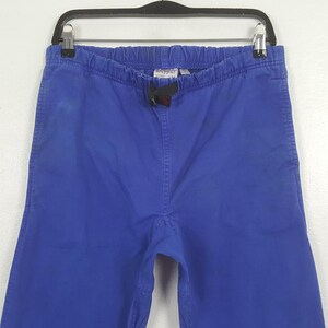 Puede incluir: Pantalones azules con cintura el&aacute;stica y cord&oacute;n. Los pantalones est&aacute;n colgados de una percha negra. Hay una peque&ntilde;a etiqueta cerca de la cintura.