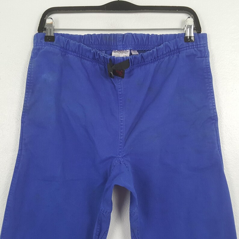 Puede incluir: Pantalones azules con cintura el&aacute;stica y cord&oacute;n. Los pantalones est&aacute;n colgados de una percha negra. Hay una peque&ntilde;a etiqueta cerca de la cintura.