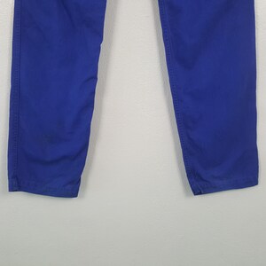 Puede incluir: Primer plano de unos pantalones azules. Los pantalones son de un color azul s&oacute;lido y vibrante. La imagen muestra la parte inferior de los pantalones, con las piernas ligeramente separadas. La tela parece ser un material resistente, con costuras visibles a lo largo de las costuras.