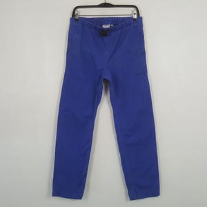 Puede incluir: Un pantal&oacute;n azul vibrante colgado de una percha negra. El pantal&oacute;n tiene cintura con cord&oacute;n y un corte relajado. La tela parece ser de algod&oacute;n resistente o material similar, adecuado para uso casual.