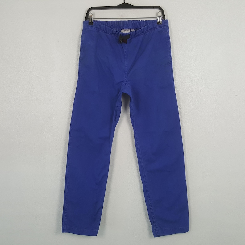 Puede incluir: Un pantal&oacute;n azul vibrante colgado de una percha negra. El pantal&oacute;n tiene cintura con cord&oacute;n y un corte relajado. La tela parece ser de algod&oacute;n resistente o material similar, adecuado para uso casual.