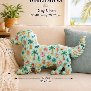 May include: A dog-shaped throw pillow with a light blue background featuring a tropical pattern of palm trees, hibiscus flowers, pineapples, and surfboards. The pillow measures 12 inches by 8 inches as indicated by the printed text dimensions.