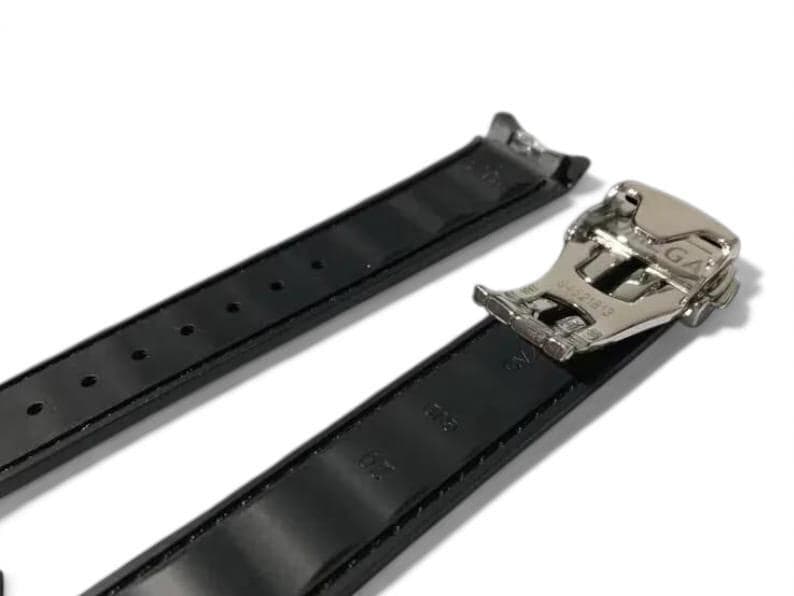 K&ouml;nnte beinhalten: Schwarzes Leder-Armband mit silberfarbener Schlie&szlig;e. Das Armband ist in zwei Teile geteilt, wobei die Schlie&szlig;e an einem Ende befestigt ist. Das Armband hat mehrere L&ouml;cher zur Anpassung.