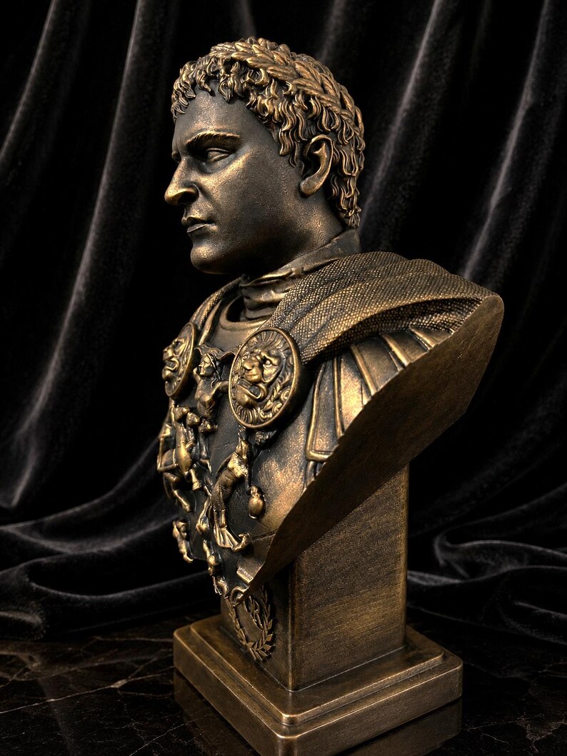 Pode incluir: Busto de cor bronze de um imperador romano, com tra&ccedil;os faciais detalhados e uma coroa de louros. O busto inclui uma armadura ornamentada com medalh&otilde;es de le&atilde;o e &eacute; montado sobre uma base retangular. Fundo escuro e texturizado.