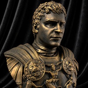 Pode incluir: Busto de cor bronze de um homem com cabelo curto e encaracolado e uma express&atilde;o s&eacute;ria. O busto apresenta uma armadura detalhada com medalh&otilde;es de le&atilde;o e esculturas em relevo. O fundo &eacute; um tecido escuro e texturizado.