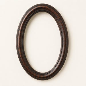 May include: An oval picture frame featuring a dark brown finish with a subtle, mottled texture throughout the surface. The frame has a smooth, rounded profile with concentric ridges that follow the curved shape of the oval opening.