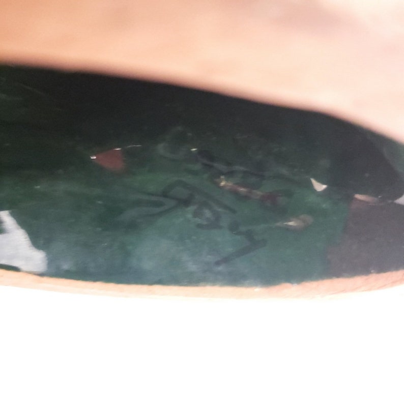 Puede incluir: Primer plano de la parte inferior de un jarr&oacute;n de cer&aacute;mica verde con una firma manuscrita en negro que dice "Made in Italy".