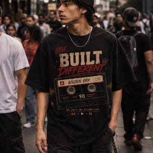 May include: Black t-shirt with the text "STILL BUILT DIFFERENT" and a cassette tape graphic. The shirt also has the text "A GOLDEN ERA" and "NO SKIP. NO ALGORITHM."