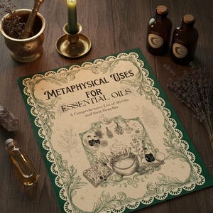 Puede incluir: Imagen de naturaleza muerta con un libro titulado "Metaphysical Uses for Essential Oils" con bordes verdes decorativos. La escena incluye una vela verde encendida, pequeñas botellas marrones, un mortero y una maja, y hierbas secas.