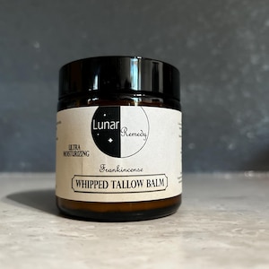 May include: A small, round jar of Lunar Remedy whipped tallow balm. The jar is dark amber glass with a black lid. The label reads "Frankincense Whipped Tallow Balm" with the words "Ultra Moisturising" above it. The Lunar Remedy logo is a crescent moon and stars.
