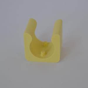 Könnte beinhalten: Ein hellgelbes, U-förmiges Schaumstoffobjekt mit abgerundeten Kanten und einer flachen Basis. Zwei kleine, zylindrische Vorsprünge sind auf der Basis sichtbar. Das Objekt hat eine glatte, matte Oberfläche.