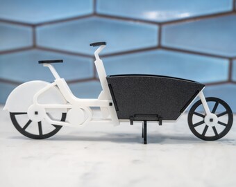 Pode incluir: Uma bicicleta de carga branca com uma caixa de carga preta. A bicicleta tem um guidão preto e rodas pretas.