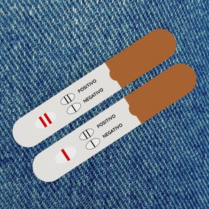 Pode incluir: Dois testes de gravidez com tampas marrons e corpos brancos, um mostrando um resultado positivo com duas linhas vermelhas, o outro um resultado negativo com uma linha vermelha. Em um fundo de ganga azul.